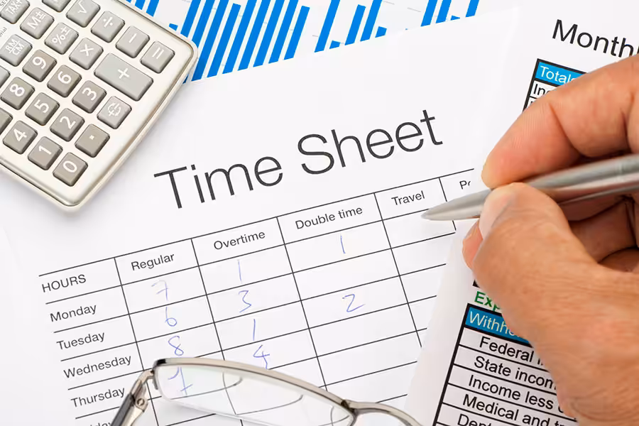 A man writes out a timesheet by hand and calculates his regular and overtime hours for a Monday through Friday workweek.
