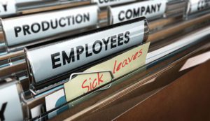 A filing cabinet drawer filled with brown folders includes a file tracking employees' accrued paid sick leave at a company.