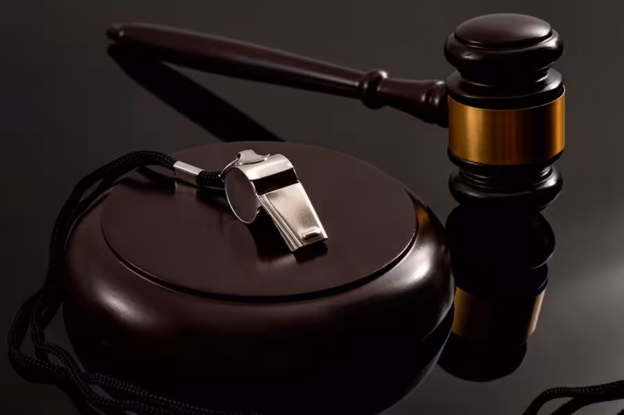  Metal whistle and wooden judge gavel on dark background.  