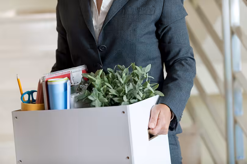 Man holding a box of office supplies walkin